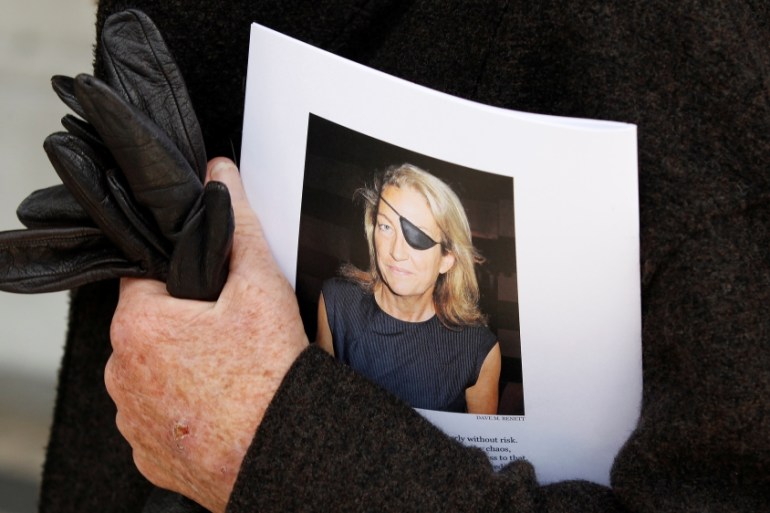 File photo of a man holding a sign honoring Sunday Times journalist Marie Colvin after a memorial service, outside St Martin in the Field in London