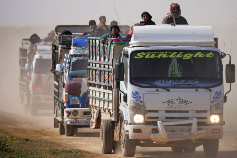 Trucks loaded with civilians ride near the village of Baghouz, Deir Al Zor province