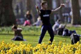 People enjoy their lunch break in a park during a sunny day as daffodils bloom in London, Friday, Feb. 22, 2019
