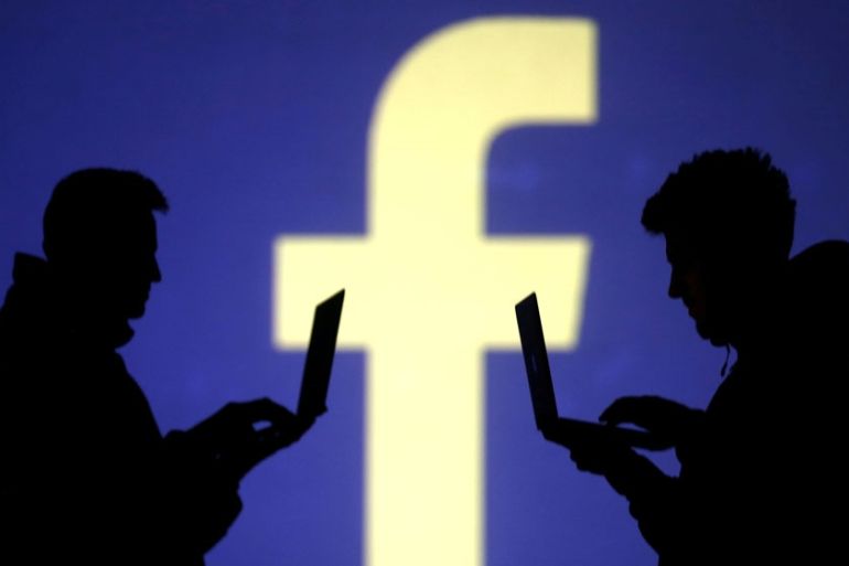 FILE PHOTO: Silhouettes of laptop users are seen next to a screen projection of Facebook logo in this picture illustration taken March 28, 2018. REUTERS/Dado Ruvic/Illustration/File Photo