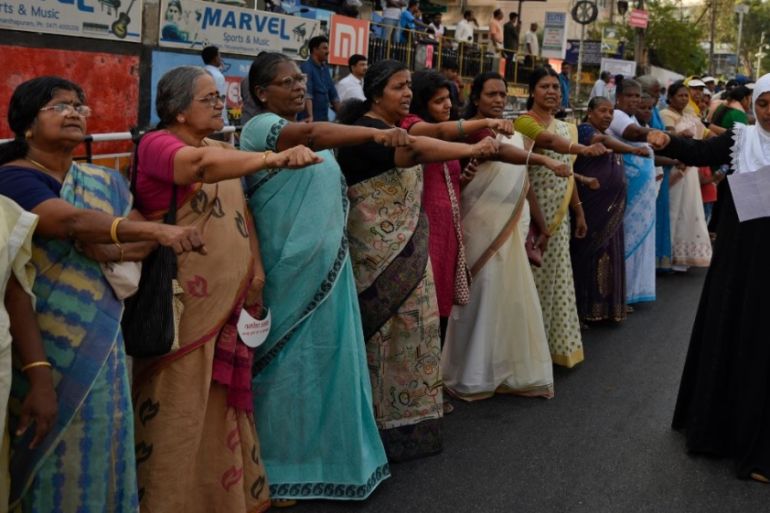 Women raise their hands to take a pledge to fight gender discrimination as they form part of a hundreds kilometer long "women''s wall" in Thiruvananthapuram
