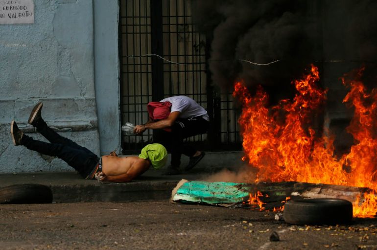 A demonstrator, left, falls after getting caught in a strand of barbed wire during clashes with the Bolivarian National Guard in Urena, Venezuela, near the border with Colombia, Saturday, Feb. 23, 201