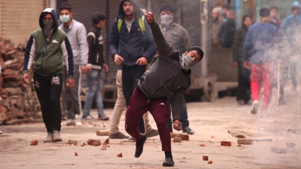 A demonstrator throws a piece of brick towards Indian police during a protest following a raid at the residence of Yasin Malik, chairman of Jammu Kashmir Liberation Front [Danish Ismail/Reuters]