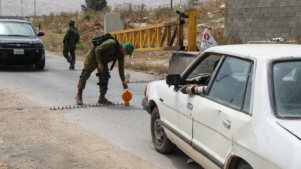 Israeli soldiers check Palestinian cars at Beit Furik checkpoint, near Nablus, West Bank on May 27, 2015 [Ahmad Al-Bazz/Activestills/Al Jazeera] 
