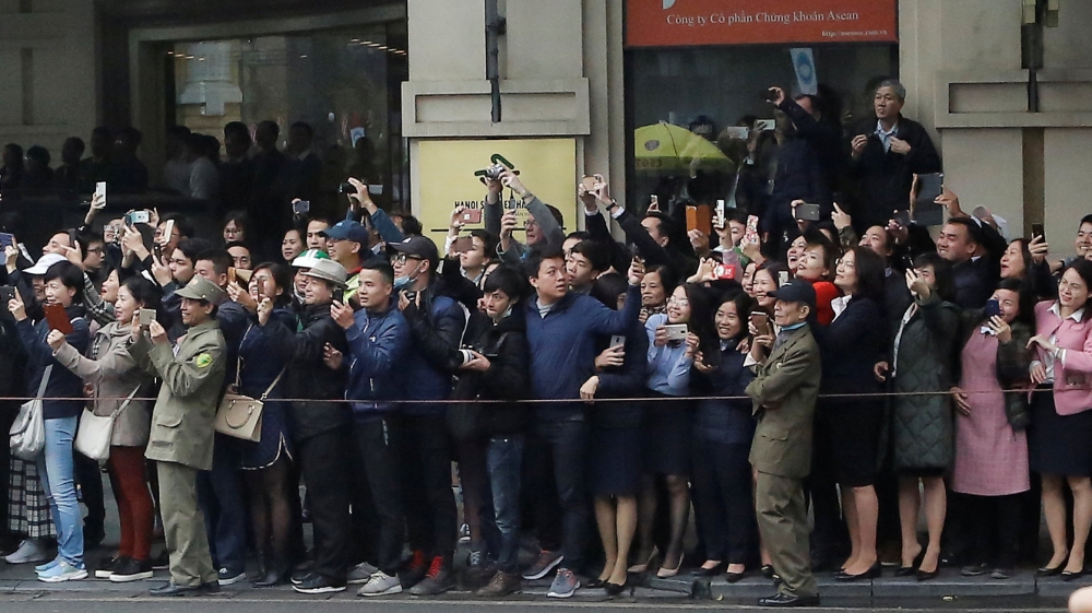 People watch Kim's motorcade as it passes the Opera House in Hanoi [Ann Wang/Reuters]