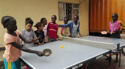 Refugees play table tennis as the leaders of the African Union meet a few kilometres away [Hamza Mohamed/Al Jazeera]