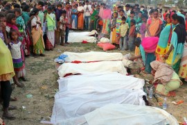 People stand next to the bodies of tea plantation workers, who died after consuming bootleg liquor, in Golaghat in the northeastern state of Assam, India, February 22, 2019