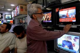A man looks at a television screen, after Pakistan shot down two Indian planes, at a shop in Karachi