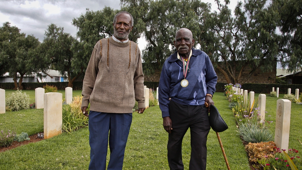 Gershon Fundi and Eusebio Mbiuki pay respects to their fallen comrades at the Nanyuki war cemetery near Mount Kenya. Both men fought for Britain in World War II [Jack Losh/Al Jazeera]