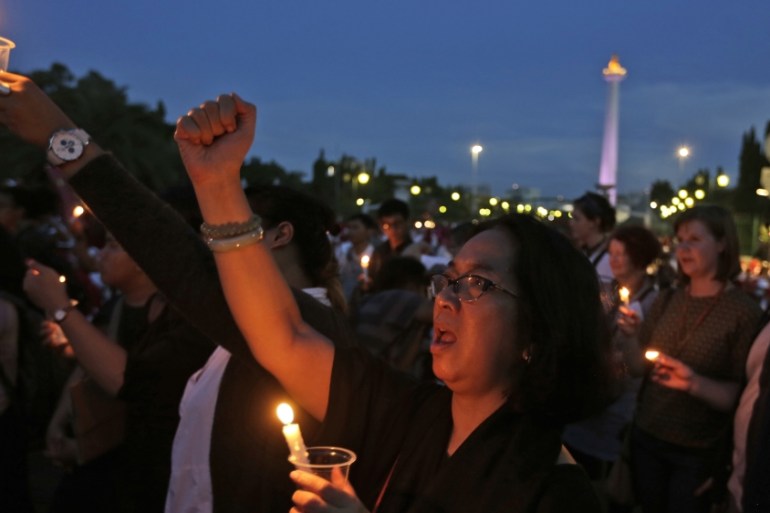 An activist holds a candle and shouts slogans during a vigil for a teenage girl who was raped and murdered