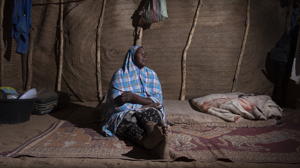 Aissa Sylla Hassan, a former worker in the Agadez migration business, sits inside her shelter. A widow, she shares the space with two other families [Francesco Bellina/Al Jazeera]