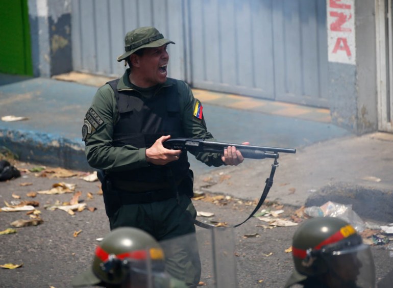 An officer of the Bolivarian National Guard fires his shotgun during clashes in Urena, Venezuela, near the border with Colombia, Saturday, Feb. 23, 2019. Venezuela''s National Guard fired tear gas on r