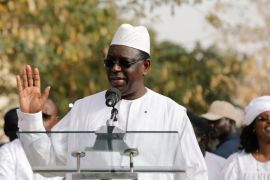 Senegal's President Macky Sall speaks after casting his vote at a polling station as his wife Marem Faye Sall stands behind in Fatick