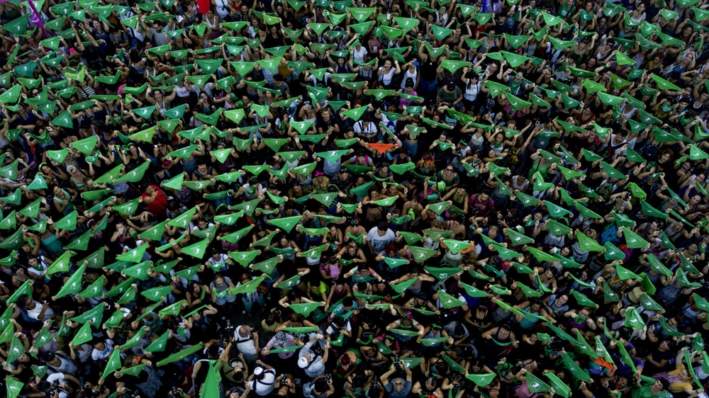 Pro-choice activists in favour of decriminalising abortion raise green handkerchiefs in Buenos Aires [Tomas F Cuesta/AP]