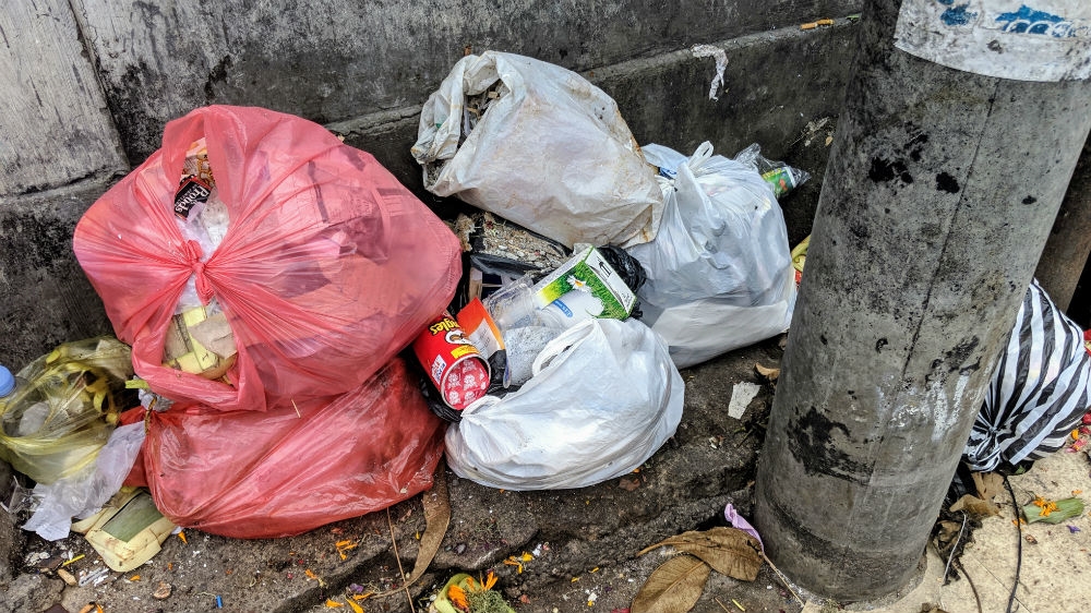 Rubbish-filled plastic bags discarded on a street in Bali. Indonesia's most popular resort island is banning the use of single-use plastics. [Kate Walton/Al Jazeera]