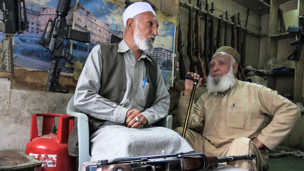 Banat Khan, left, says his family has been selling guns in this district for longer than he can remember [Asad Hashim/Al Jazeera]