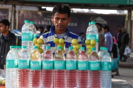A vendor selling water bottles awaits customers in the old quarters of New Delhi, India. [Nasir Kachroo/NurPhoto/Getty Images]