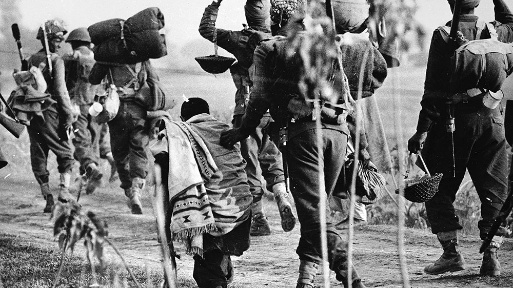 An elderly Pakistani refugee is pushed aside by Indian troops advancing into the East Pakistan (Bangladesh) area during the 1971 Indo-Pakistani war. [Getty Images]