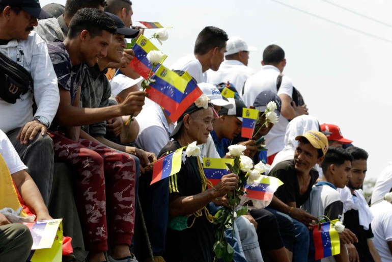 Venezuelans sit atop a semi-trailer, with national flags and white roses, accompanying U.S. humanitarian aid destined for Venezuela, in Cucuta, Colombia, Saturday, Feb. 23, 2019. The aid convoy is loo