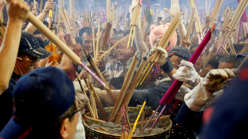People rush to plant the first joss stick of the Lunar New Year at the stroke of midnight at the Kwan Im Thong Hood Cho temple in Singapore [Feline Lim/Reuters]