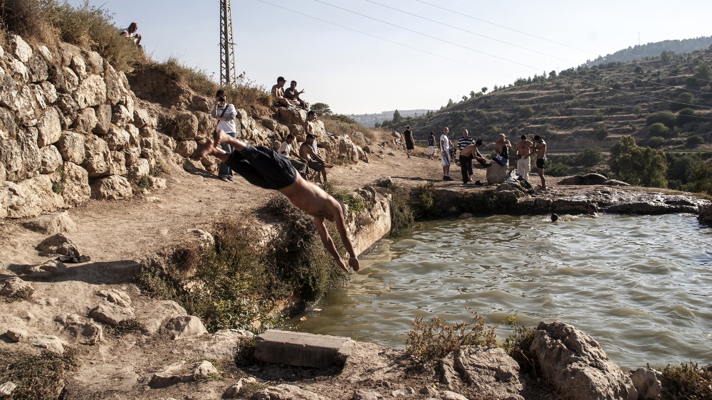 Israelis and Palestinians swim in Ein Haniya spring close to the destroyed Palestinian village of al-Walaja, near Jerusalem on July 5, 2007. Currently the spring is fenced off and out of reach for Palestinians [Anne Paq/Activestills/Al Jazeera]