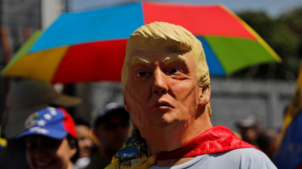 A man wearing a mask of US President Trump attends a rally against the government in Caracas [Carlos Barria/Reuters]