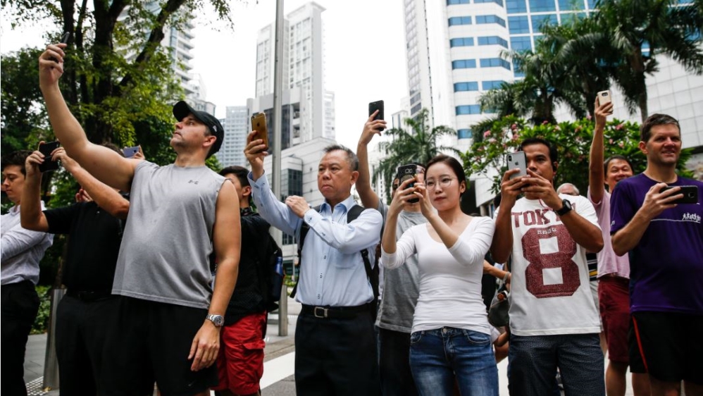Members of the public in Singapore take photos of Kim's motorcade [Yong Teck Lim/AP Photo]