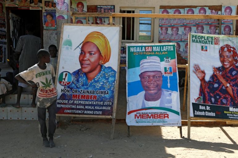 Boys stand near campaign posters for candidates running for office in the Feb. 16 elections, at the Teachers'' Village IDP camp in Maiduguri