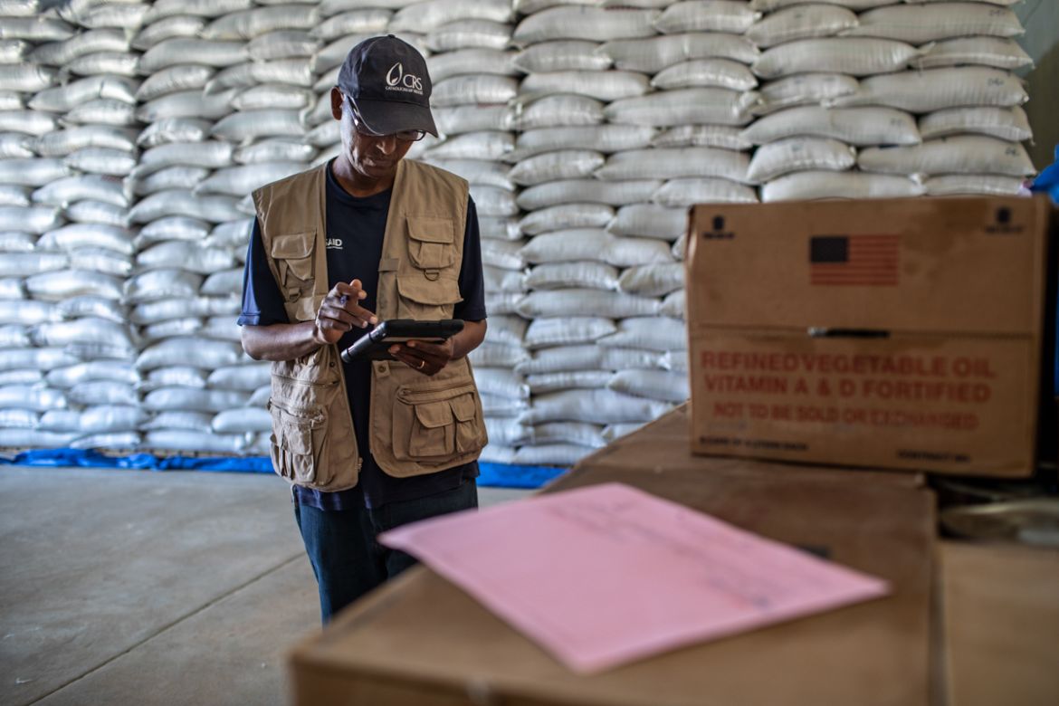 Gebregziabher Assefa, a CRS field officer, uses a tablet while looking over commodities at a warehouse where food for the Joint Emergency Operation Program (JEOP) is stored in Hawzen district, Misraqa