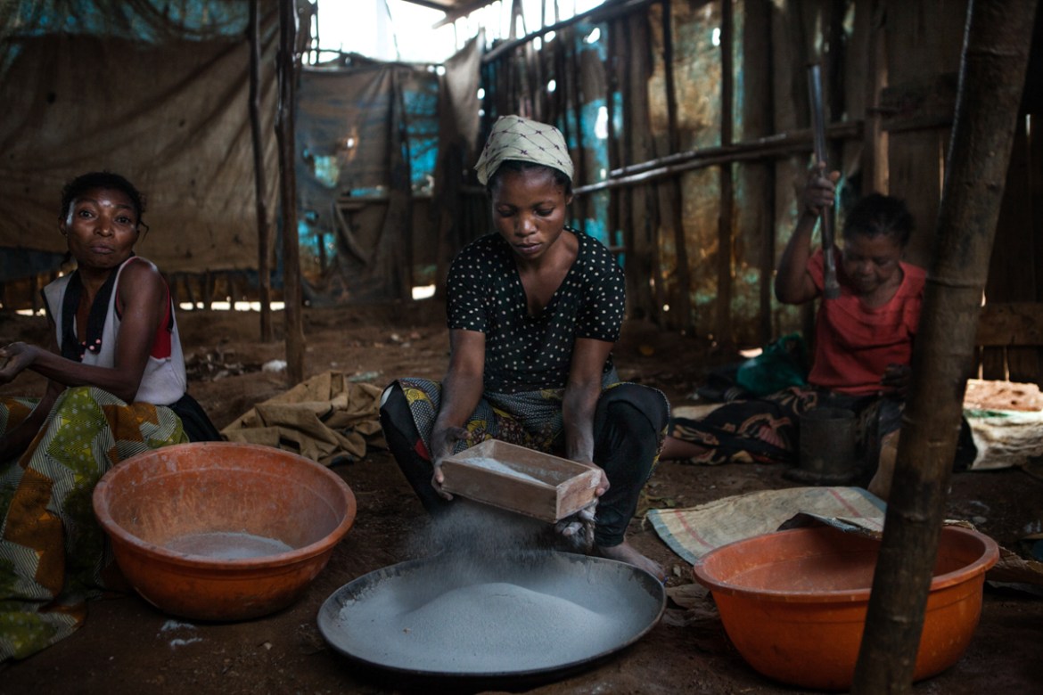 Kamituga gold mining site. A woman is sifting the quartz powder previously crushed by either the grinding machines or the mama twangaises. It takes several hands to obtain the fine powder, which will
