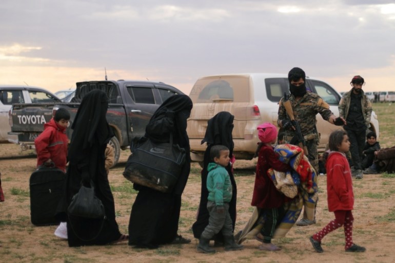 Women walk with children near the village of Baghouz, Deir Al Zor province