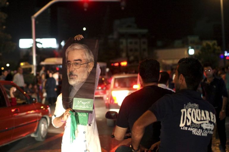 A supporter of Iranian presidential candidate Hasan Rouhani holds up a poster of Green Movement leader Mir Hossein Mousavi, who was a candidate in 2009 and is currently under house arrest