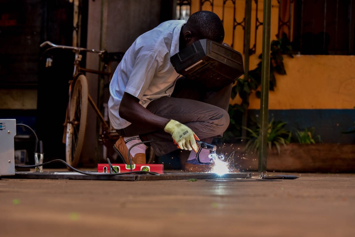 Nkuutu Brian Jeremiah, a field officer at FABIO welding parts on an ambulance carrier being constructed at their office in Jinja. The ambulances are made in Uganda with locally sourced materials and b
