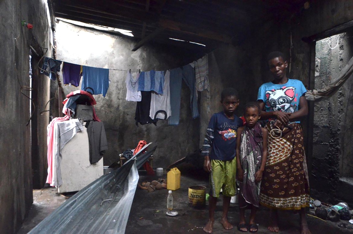 A displaced family from Beira pose for a photograh as they take shelter in a structure on March 19, 2019. - More than a thousand people are feared to have died in a cyclone that smashed into Mozambiqu