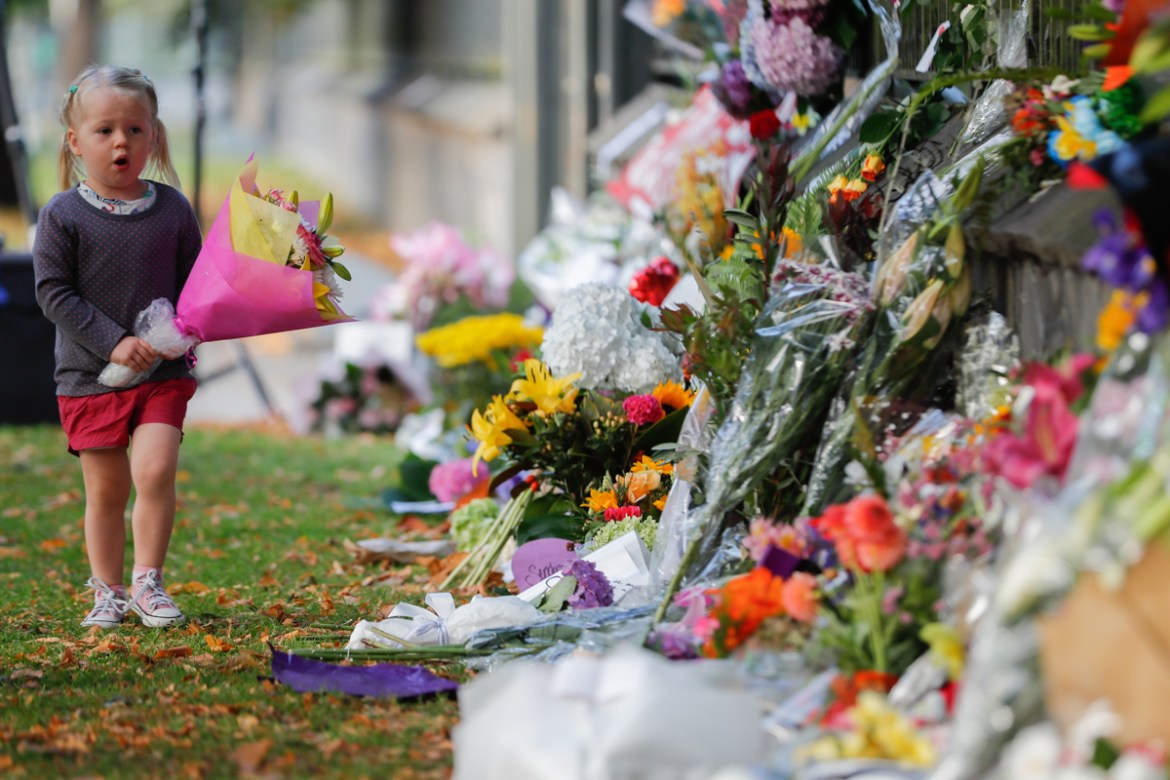 A girl walk to lay flowers on a wall at the Botanical Gardens in Christchurch, New Zealand, Sunday, March 17, 2019. New Zealand''s stricken residents reached out to Muslims in their neighborhoods and a