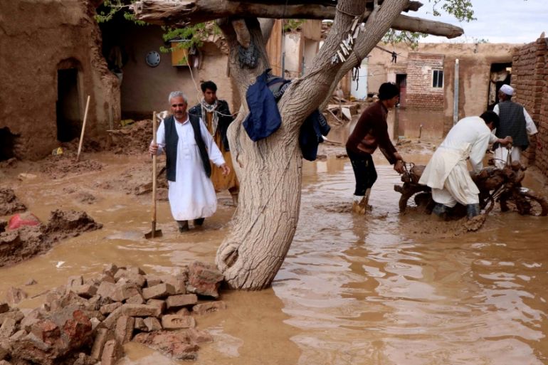 People salvage items from a house destroyed by flood in Enjil district of Herat province