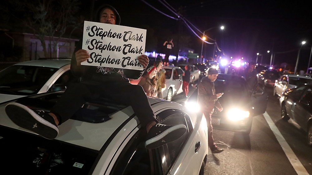 A Black Lives Matter protester holds a sign as he sits on his car blocking an intersection during a demonstration against the Sacramento police department [File: Justin Sullivan/Getty Images]