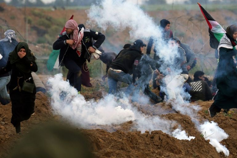 Palestinian demonstrators run away from teas gas fired by Israeli forcers during a protest at the Israel-Gaza border fence, in the southern Gaza Strip