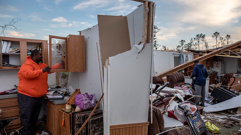 Granadas Baker (left) and son Granadas Jr ,18 (right), retrieve personal items from the damaged home where they survived a tornado a day earlier in Beauregard [David Goldman/AP Photo] 