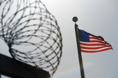FILE: A US flag flies above a razorwire-topped fence at the 'Camp Six' detention facility at US Naval Station Guantanamo Bay December 10, 2008 [File:Mandel Ngan/Reuters]