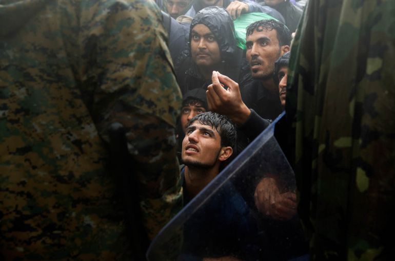 Migrants and refugees beg Macedonian policemen to allow passage to cross the border from Greece into Macedonia during a rainstorm, near the Greek village of Idomeni, September 10, 2015. REUTERS/Yannis