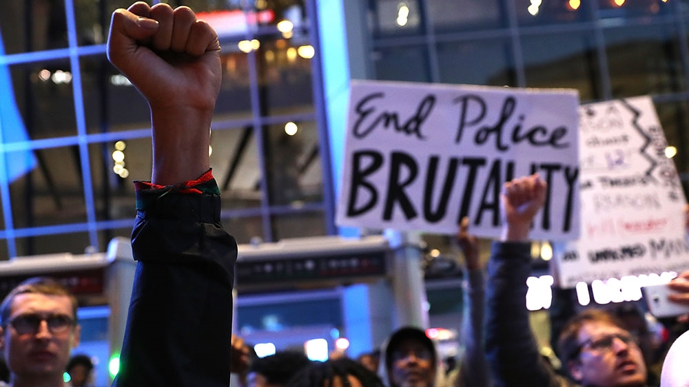 Black Lives Matter protesters hold their fists in the air as they block the entrance to the Golden 1 Center during a demonstration against the Sacramento police department [File: Justin Sullivan/Getty Images]