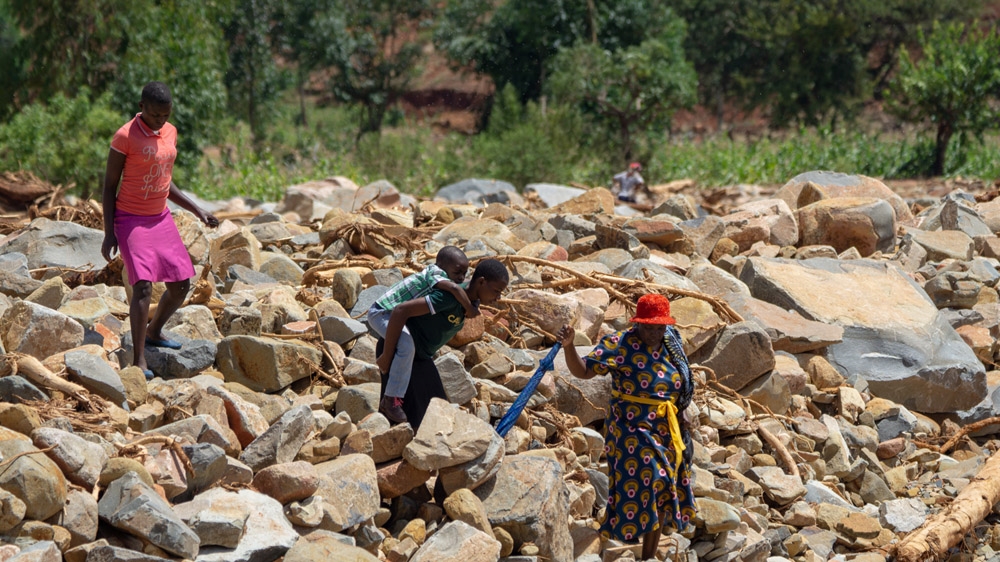 People cross a path filled with rock boulders that fell from the mountain during the storm in Chimanimani [Tendai Marima/Al Jazeera]
