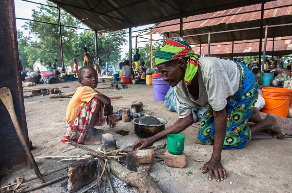 A displaced old woman prepares a fire for cooking at the Agricultural Development and Marketing Corporation (ADMARC) camp for people displaced by flash floods from recent heavy rains on March 14, 2019