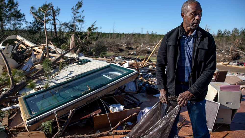 Richard Tate retrieves personal items from what's left of his home where he survived a tornado with his wife in Beauregard [David Goldman/AP Photo]