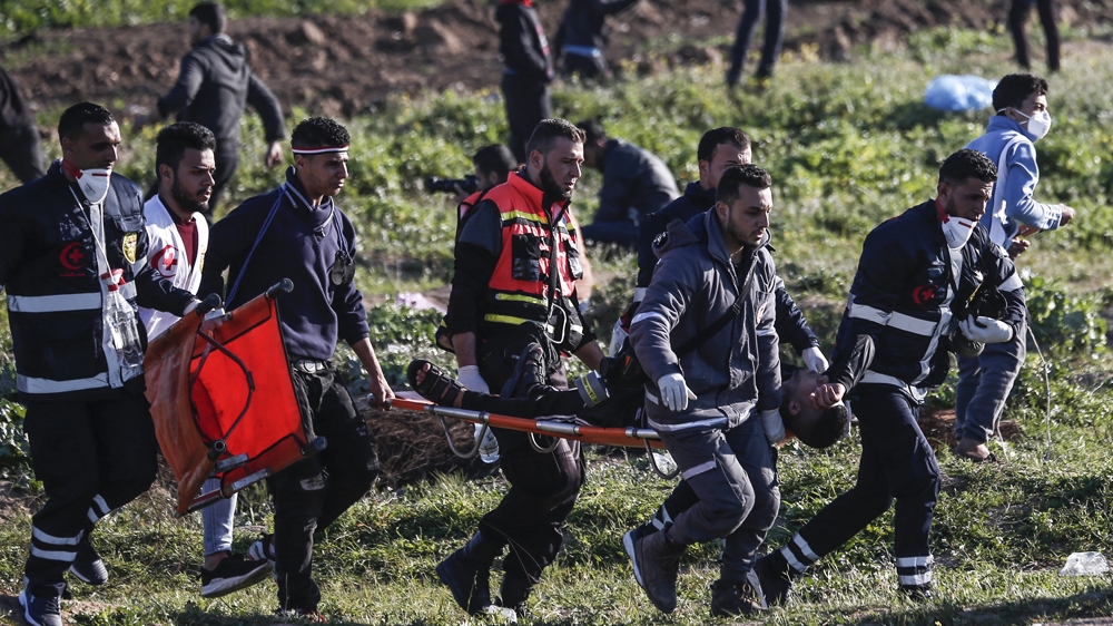 Palestinian paramedics carry a wounded protester on a stretcher during clashes with Israeli forces following a demonstration near the fence along the border with Israel, east of Gaza, on March 8, 2019 [File: Mahmud Hams/AFP]