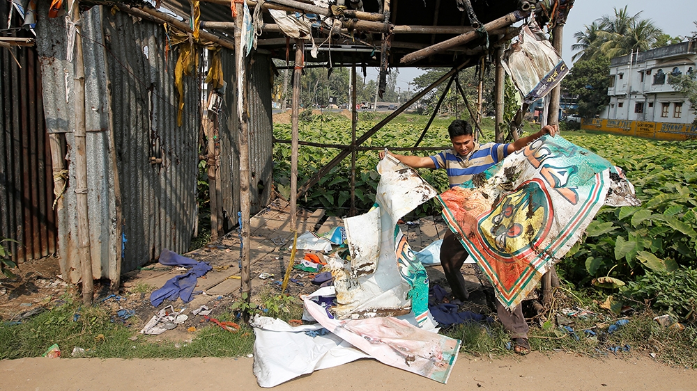 Rajiv Mondal, 36, a Trinamool Congress party supporter, shows a torn banner after his party office was burned at Kanthi in Purba Medinipur district [File: Rupak De Chowdhuri/Reuters]