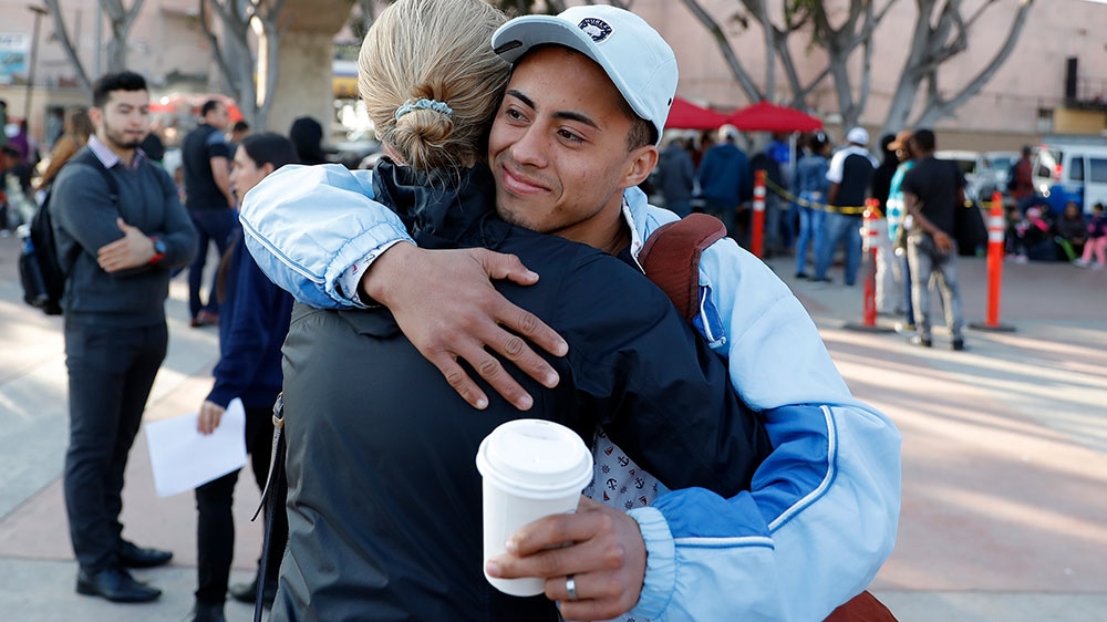 A man who only gave his first name as Ariel, of Honduras, hugs a lawyer before crossing into the United States to begin his asylum case after being returned to Mexico [Gregory Bull/AP Photo] 