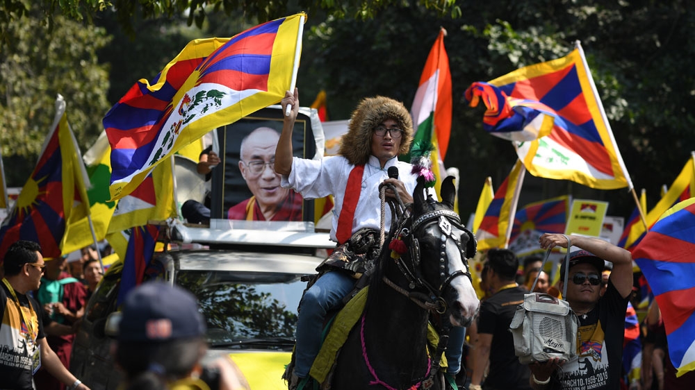A Tibetan activist riding a horse escorts a vehicle with the picture of Dalai Lama in New Delhi [Sajjad Hussain/AFP]