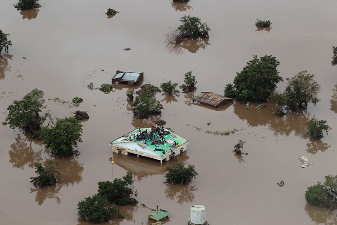 This handout picture taken and released on March 18, 2019, by the Mission Aviation Fellowship shows people on a roof surrounded by flooding in an area affected by Cyclone Idai in Beira. - A cyclone th